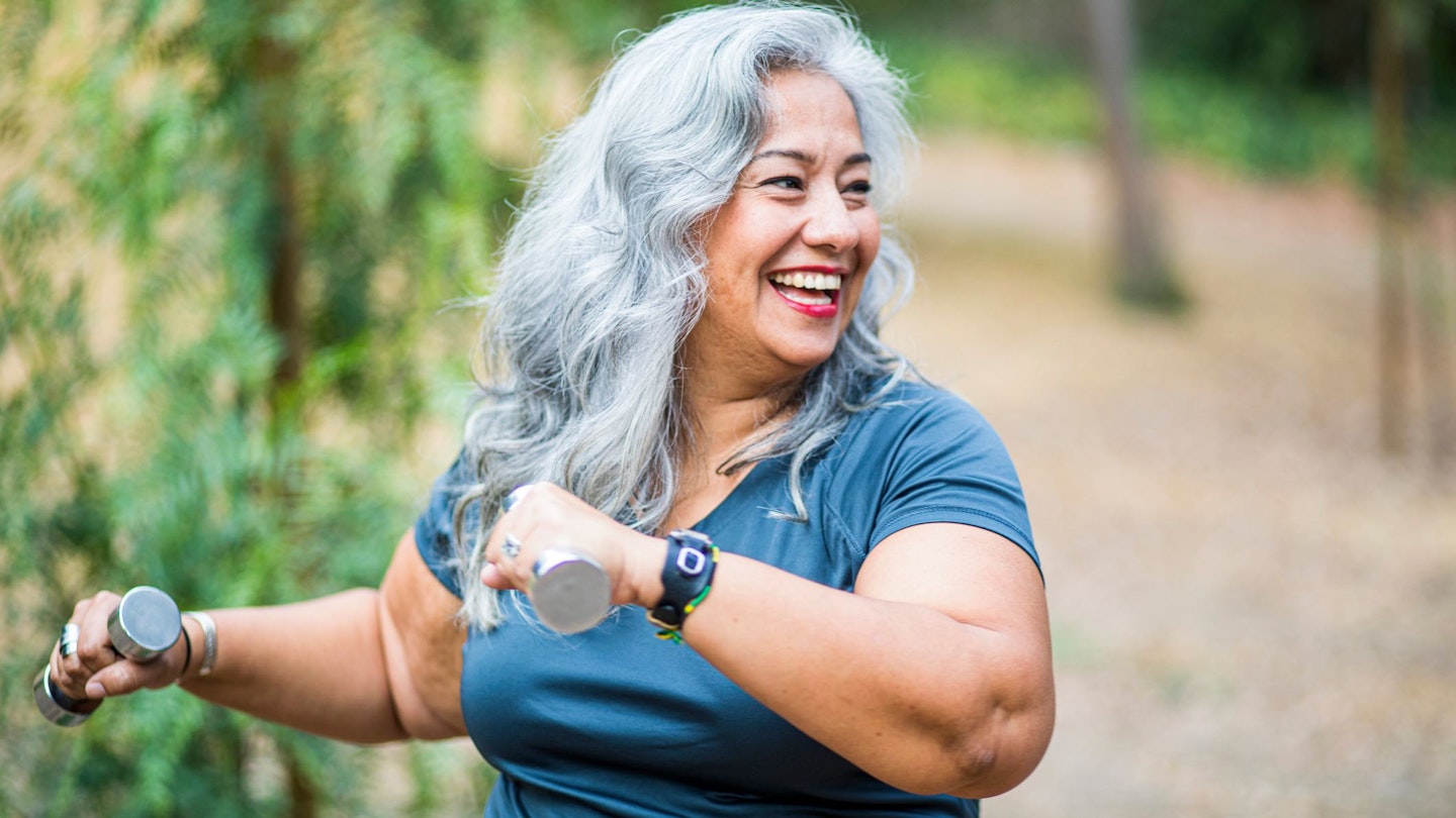 Woman in park holding dumbbells