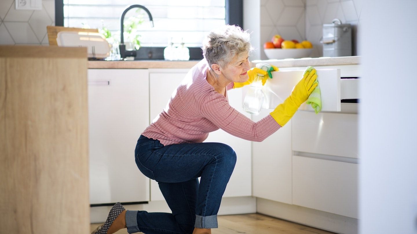 Woman cleaning kitchen cupboards