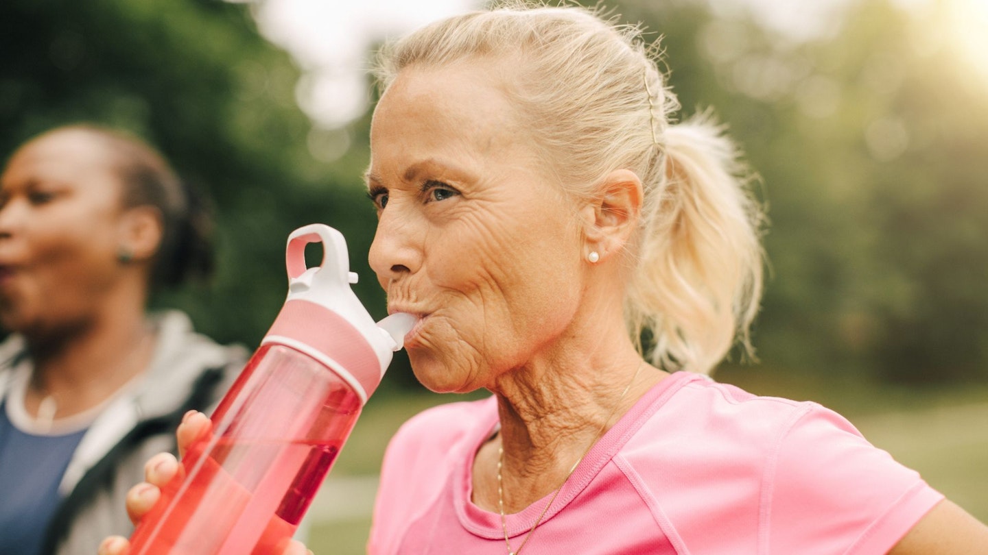 Senior woman drinking water from bottle in park