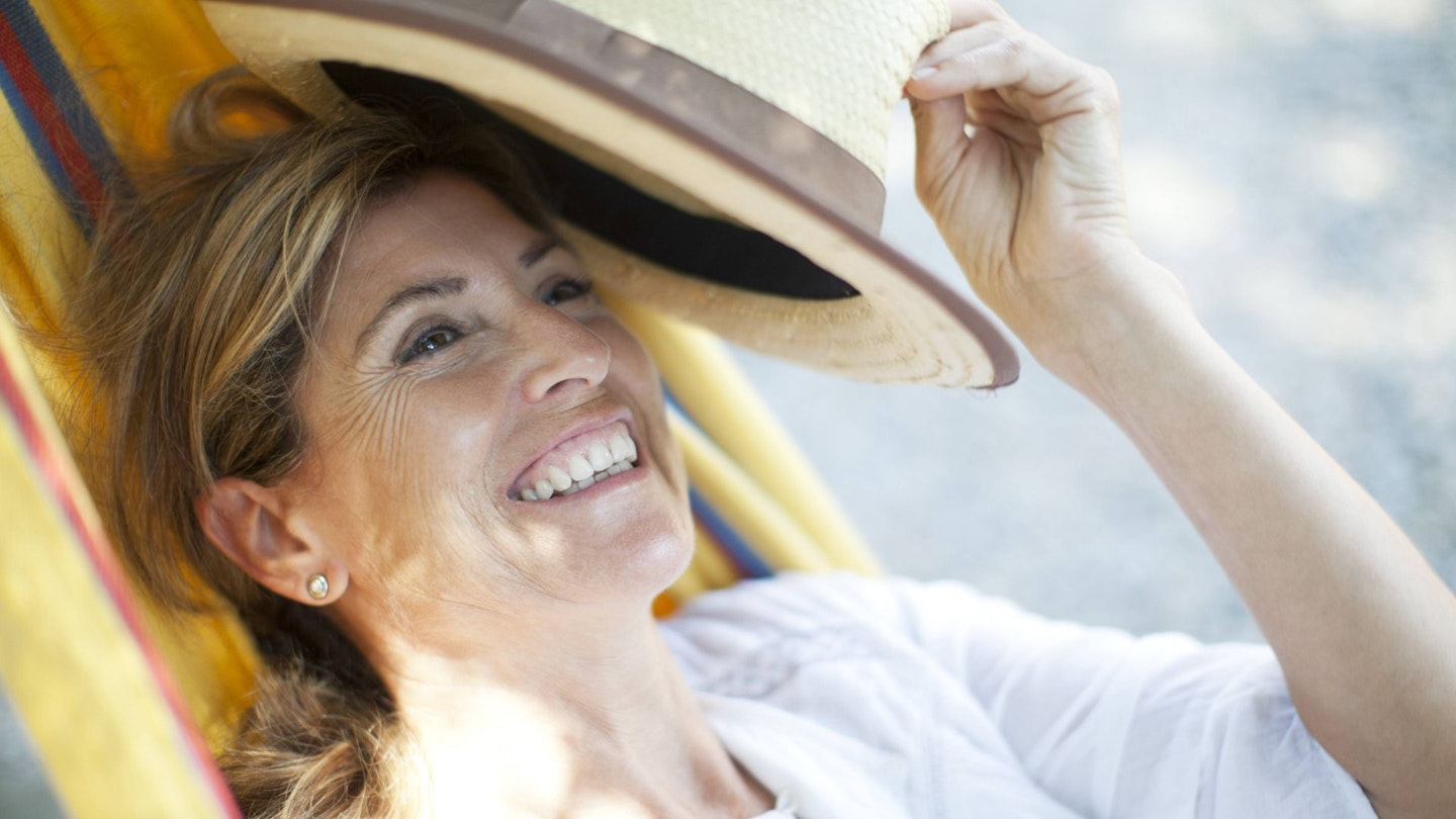 Mature lady relaxing in the sun with a straw hat