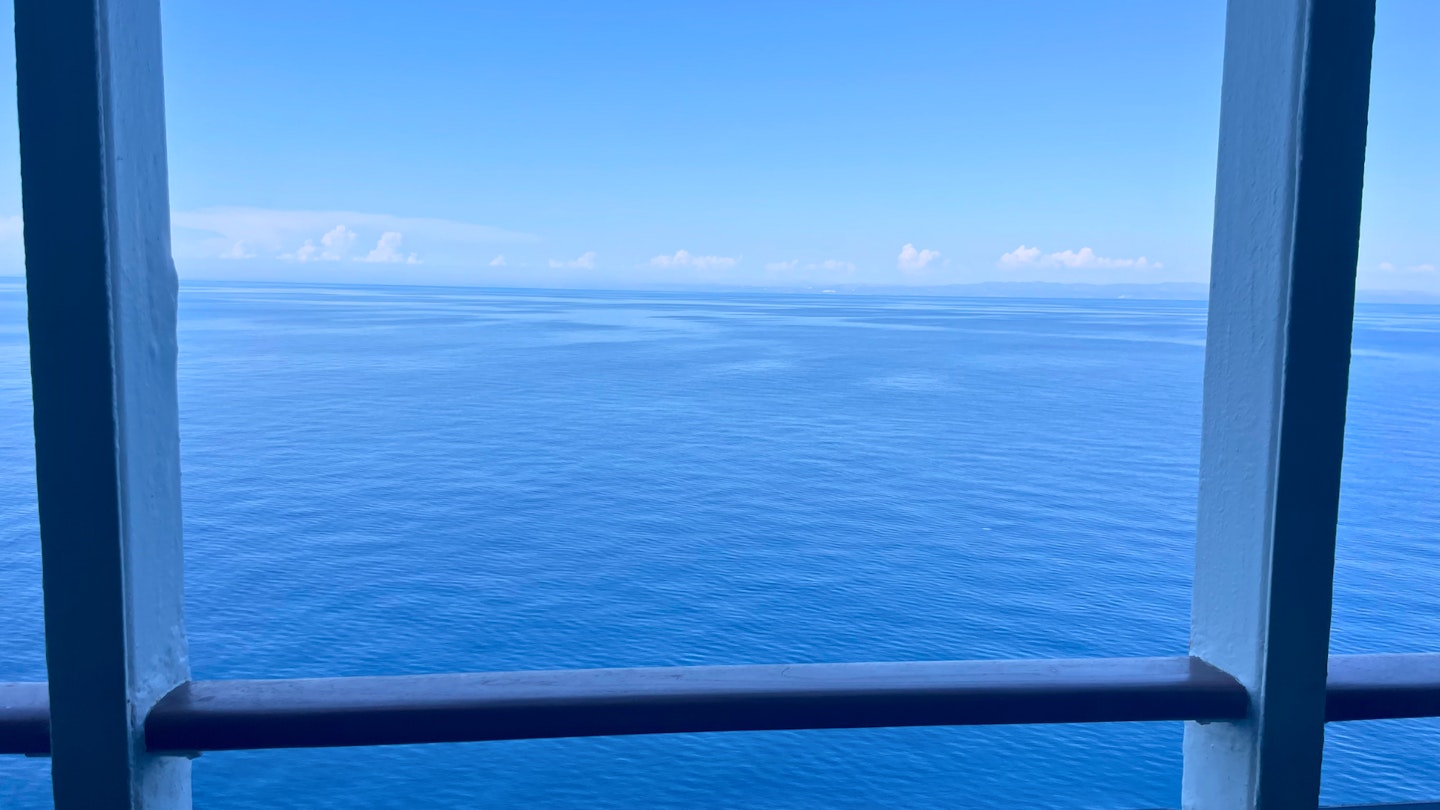 View of the sea with a cruise boat railing in the foreground.