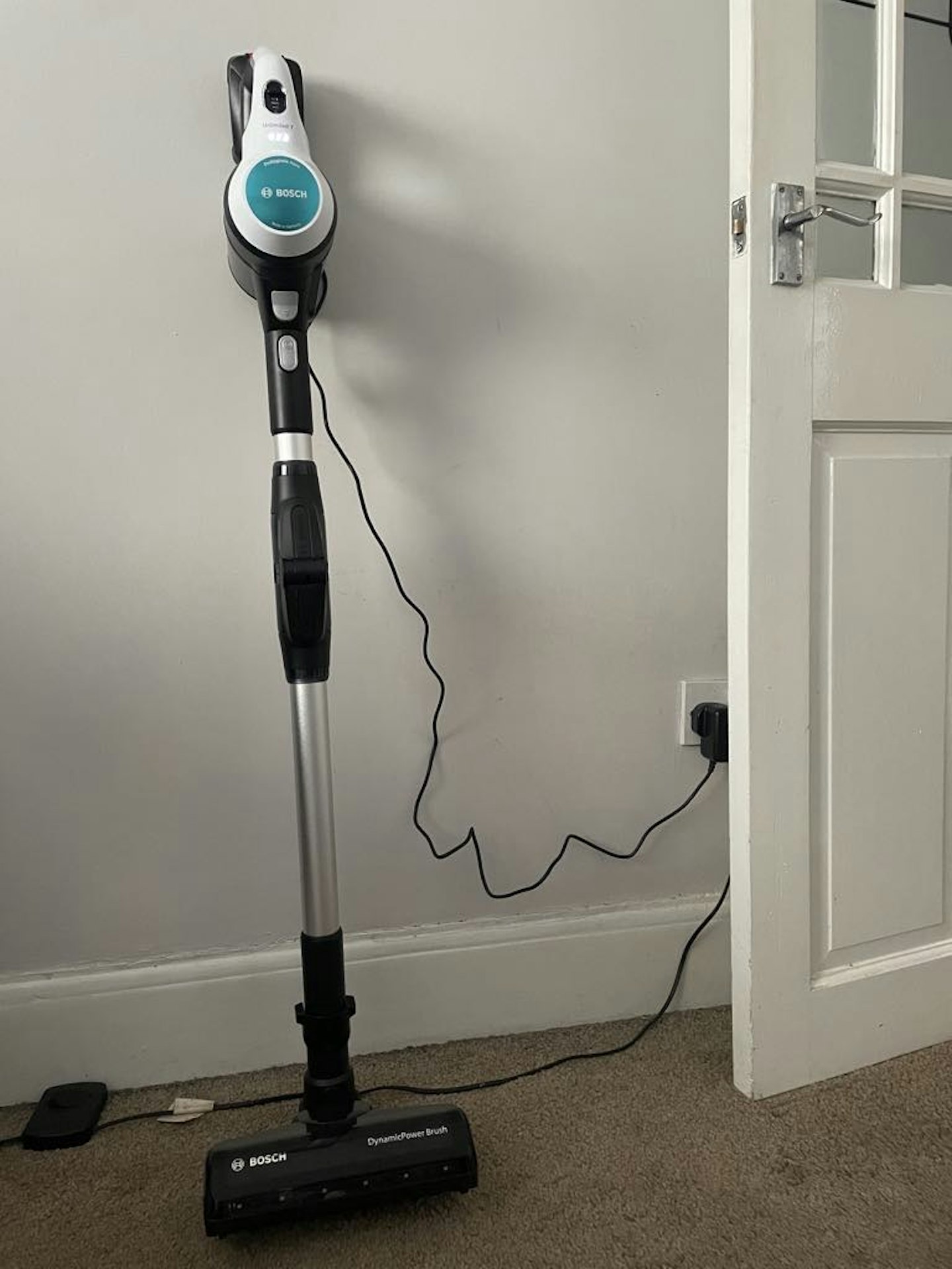 photo of the Bosch Unlimited 7 Aqua Vacuum against a wall and plugged into it's charger, home setting