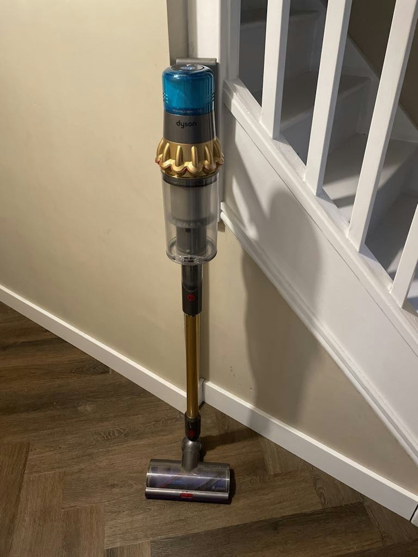 photo of Dyson V15s Detect Absolute Cordless Vacuum Cleaner in a home hallway on a hardwood floor with a part of a staircase in the background 