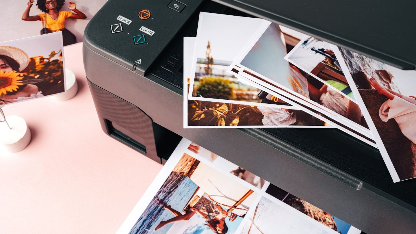 Modern laser printer printing color photos of women close up on desk