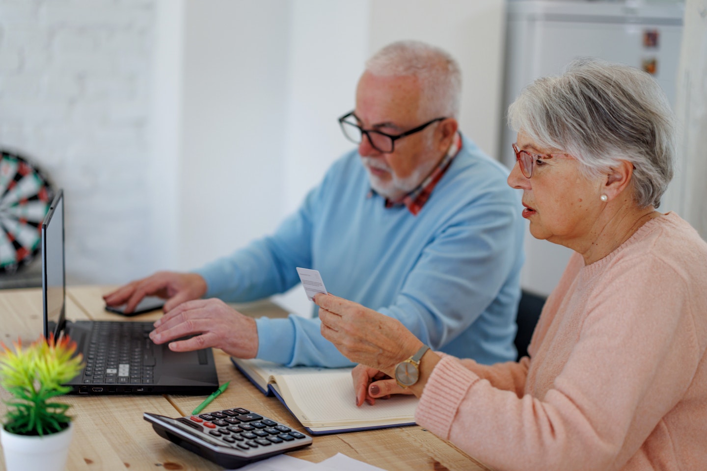 Senior Woman Holding Credit Card and Using Laptop Computer While Paying Bills at Home With Credit Card.