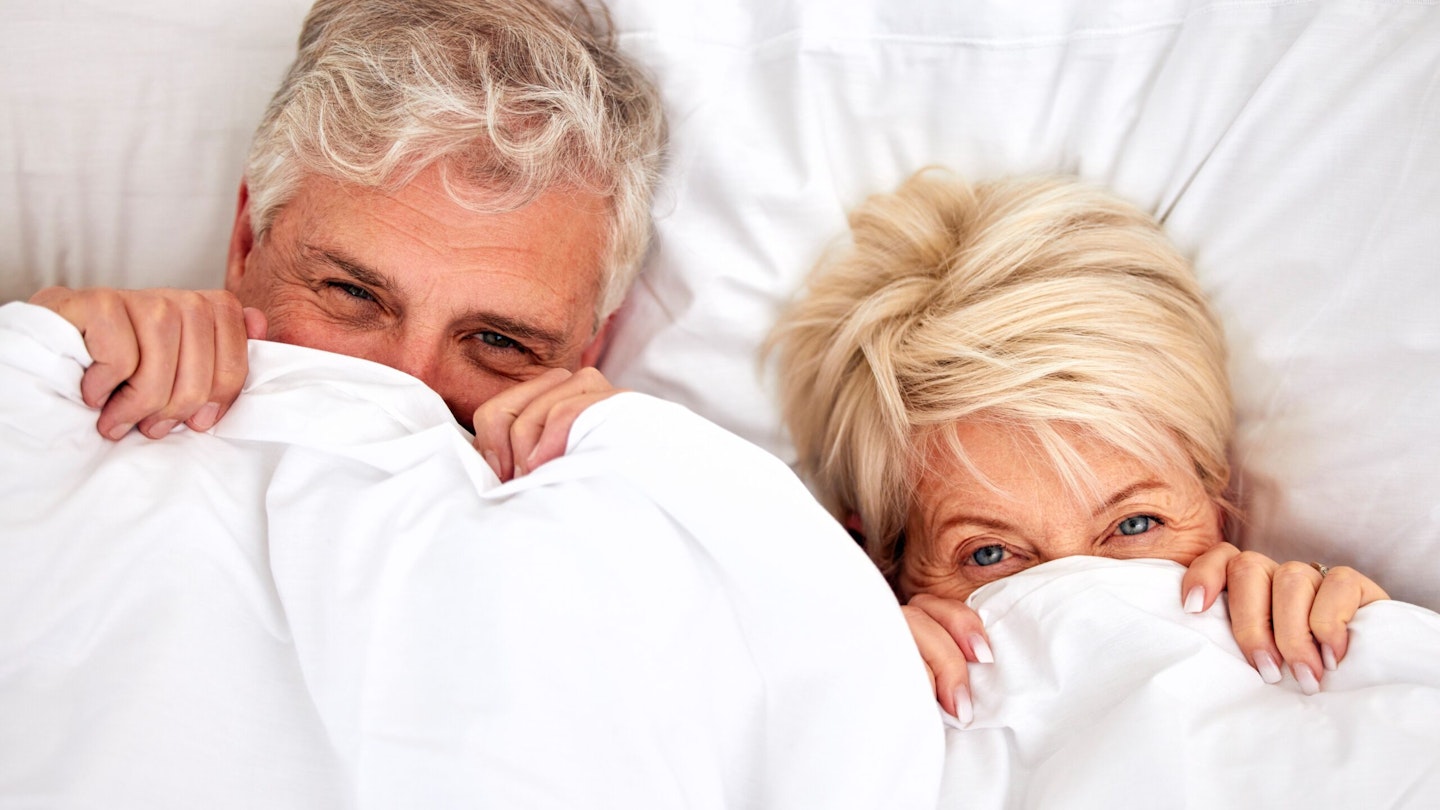 Couple in bed hiding under duvet