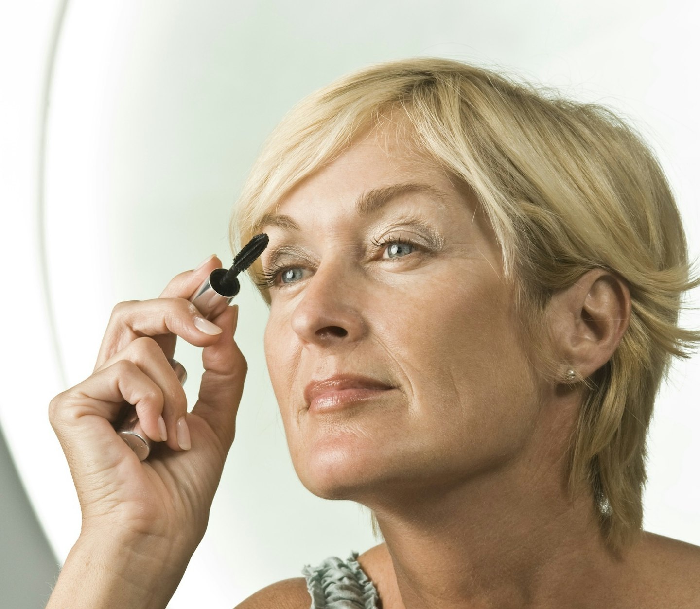 Close-up of a woman applying mascara on hooded eyes