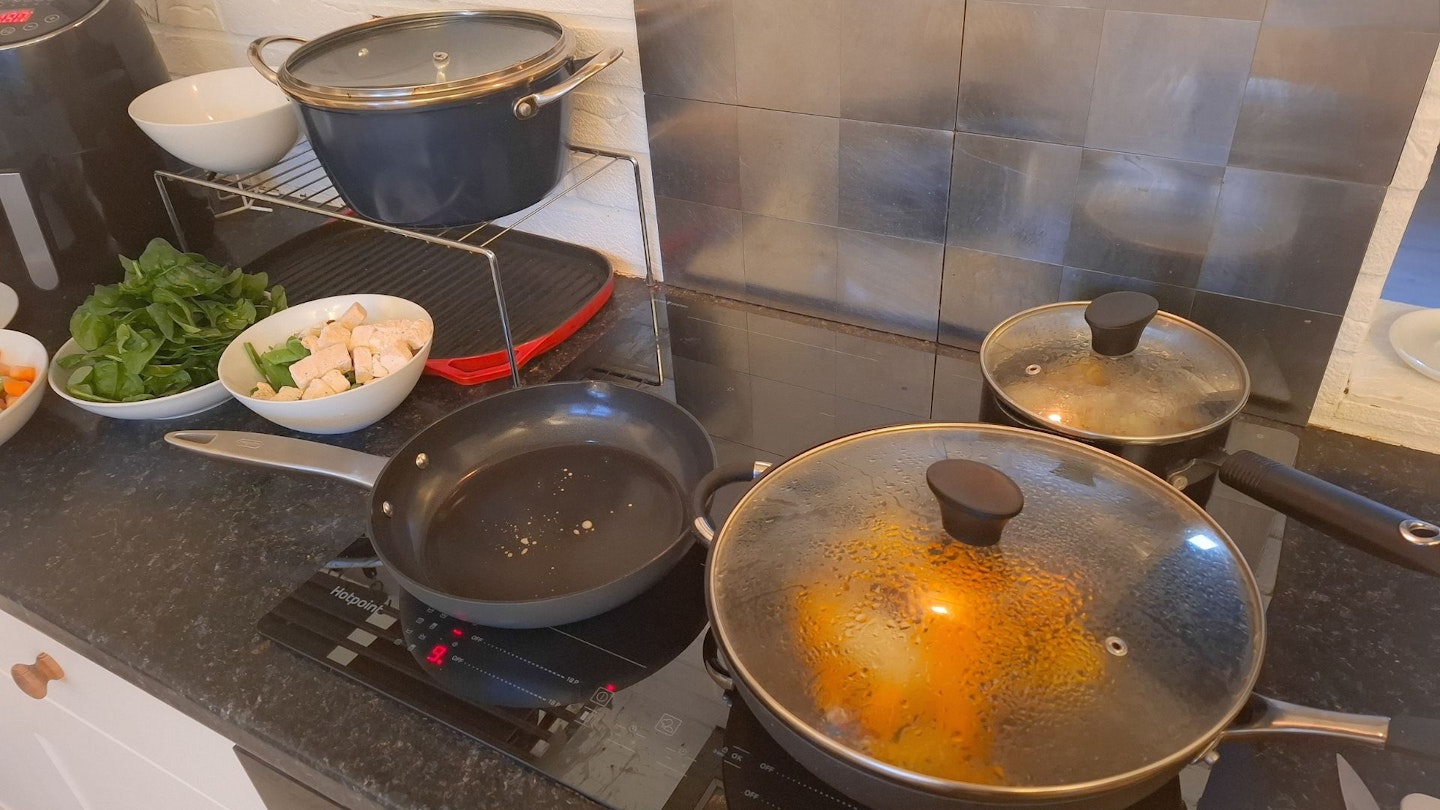 The Zyliss frying pan, Stellar wok and Blue Pro casserole pot, plus other saucepans and food that's cooking on an induction hob