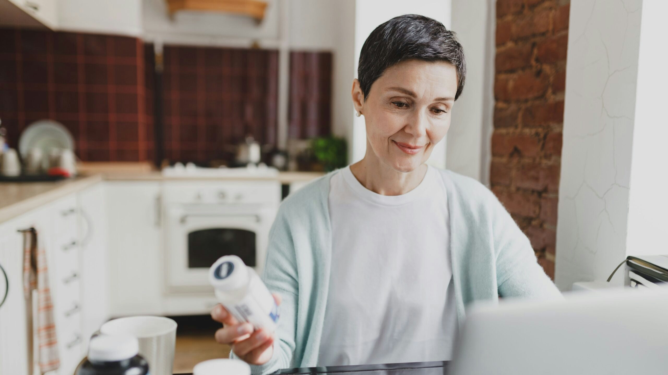 Woman looking online and holding a bottle of pills