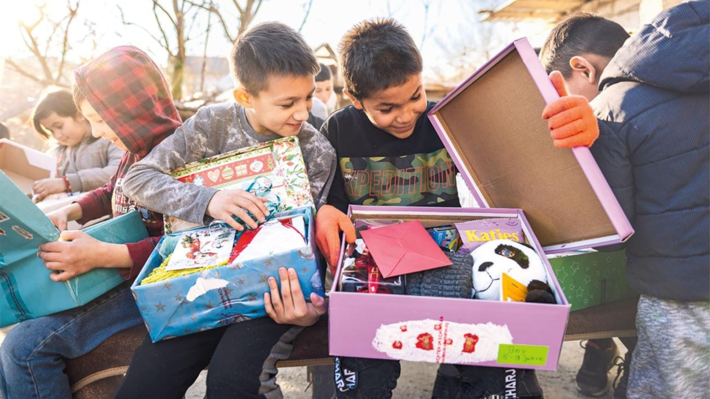 Children opening shoeboxes filled with toys and gifts