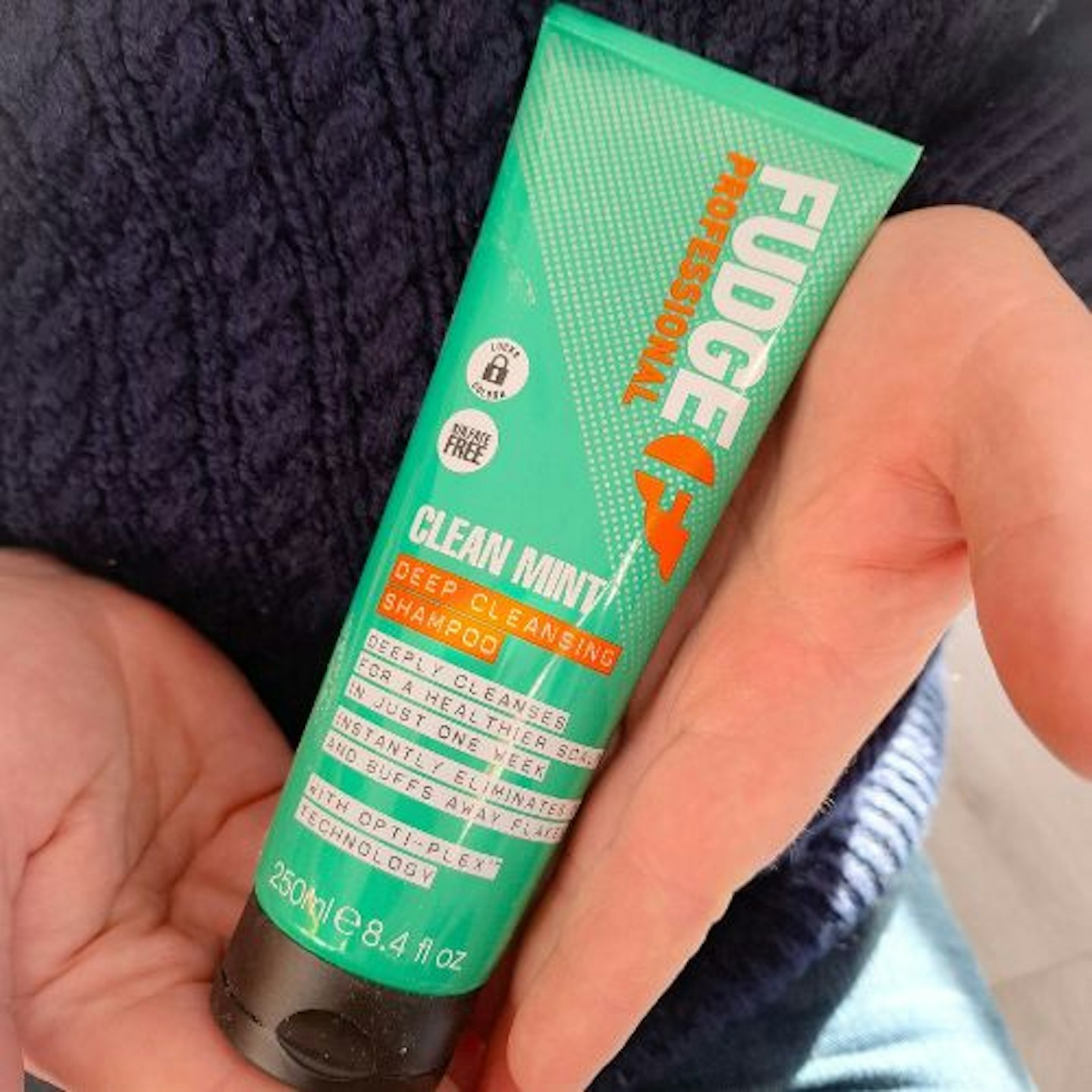 tester's hands holding a tube of Fudge Professional Clean Mint Shampoo