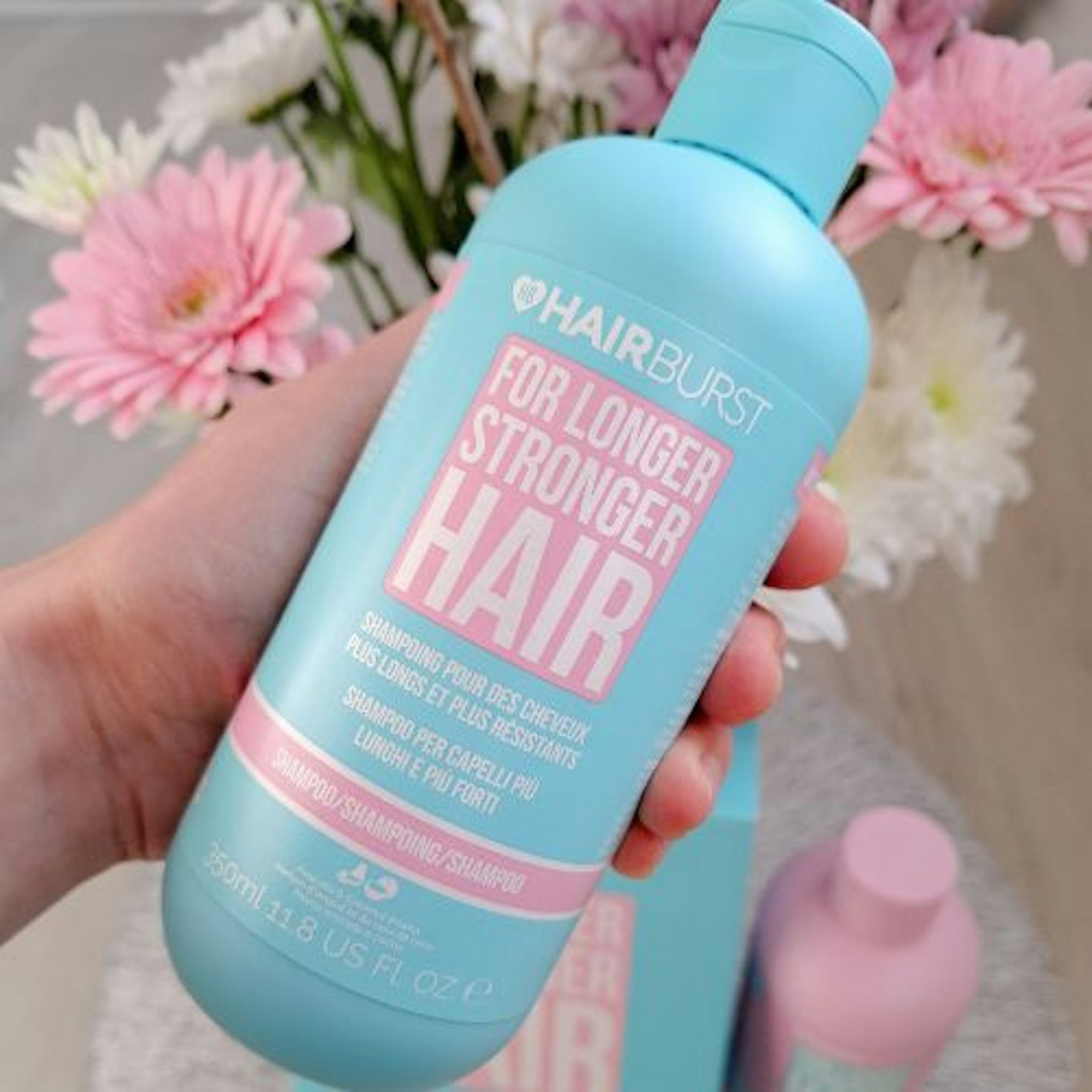 front of bottle Hairburst Shampoo & Conditioner with flowers in the background