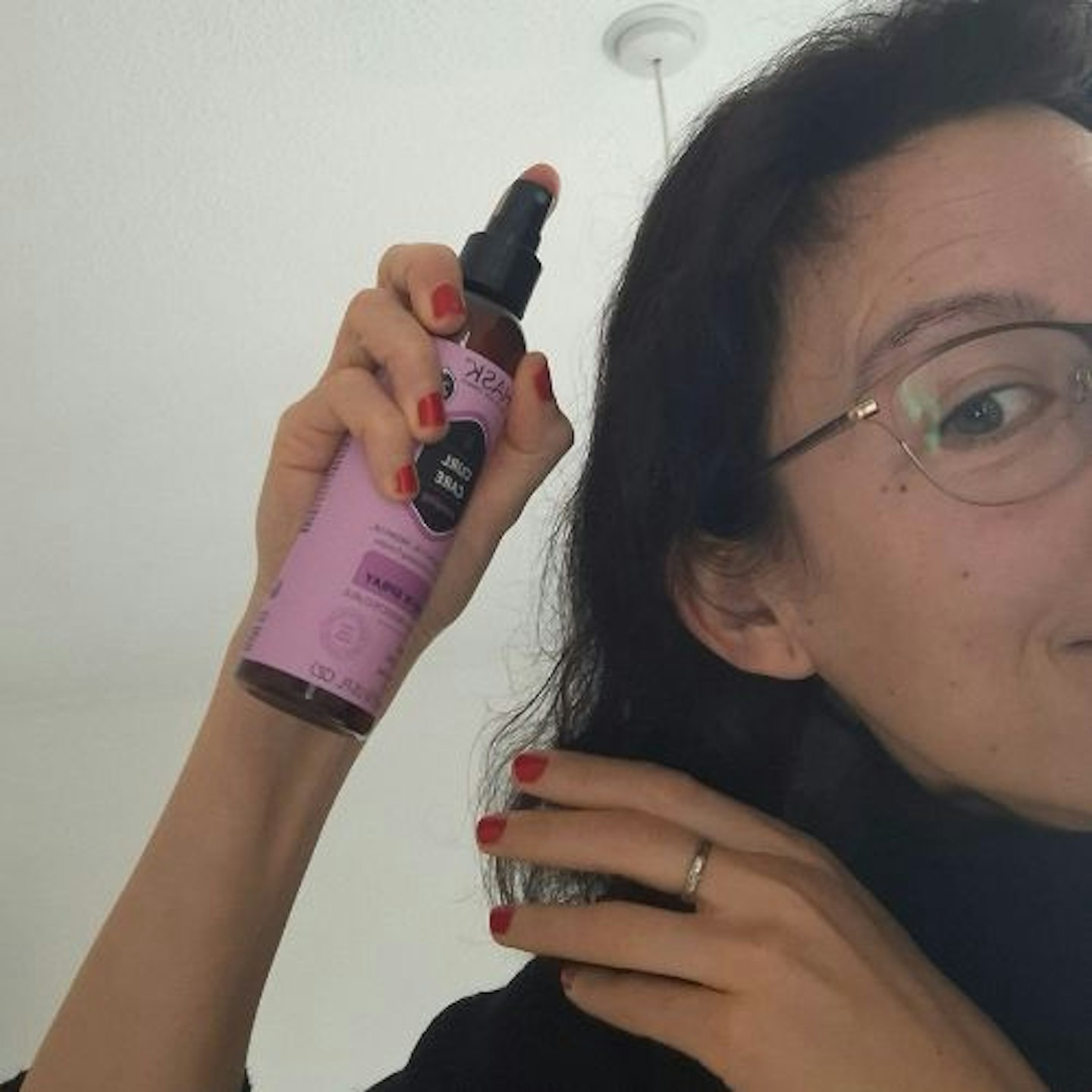 Our tester applies Hask Curl Care Smooth 5-in-1 Leave-in Spray to her unstyled dark brown hair, side view