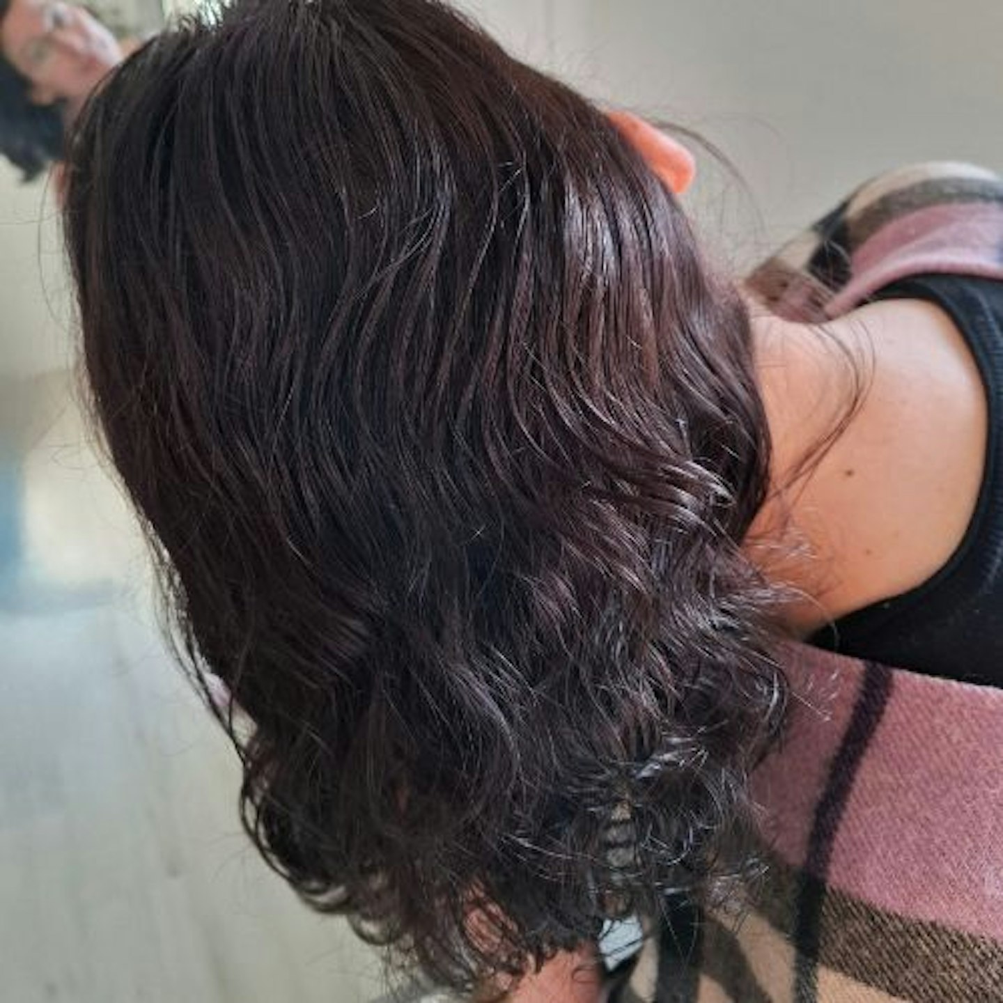 Back of tester's wavy dark brown hair, with leave-in spray applied, before styling