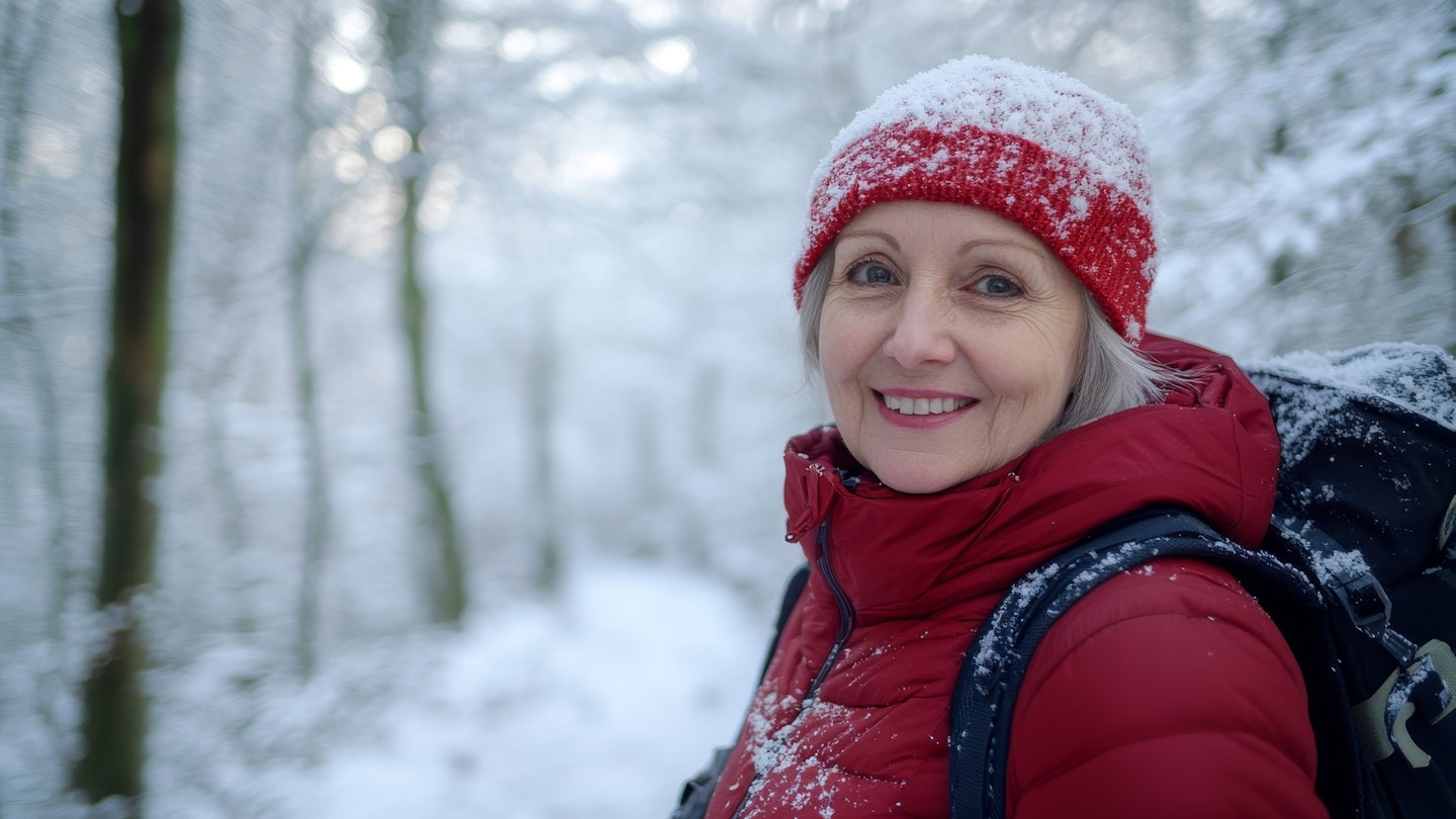 Mature senior woman hiking in winter snowy forest