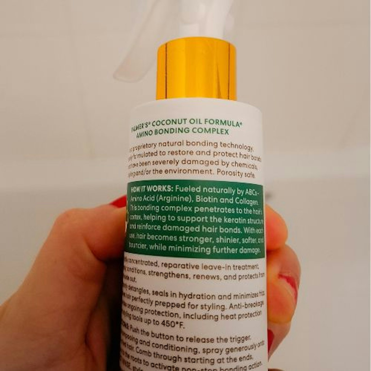 close up photo of back of bottle text, Palmer’s Amino Bonding Complex Bonding Leave-In Treatment in tester's hand