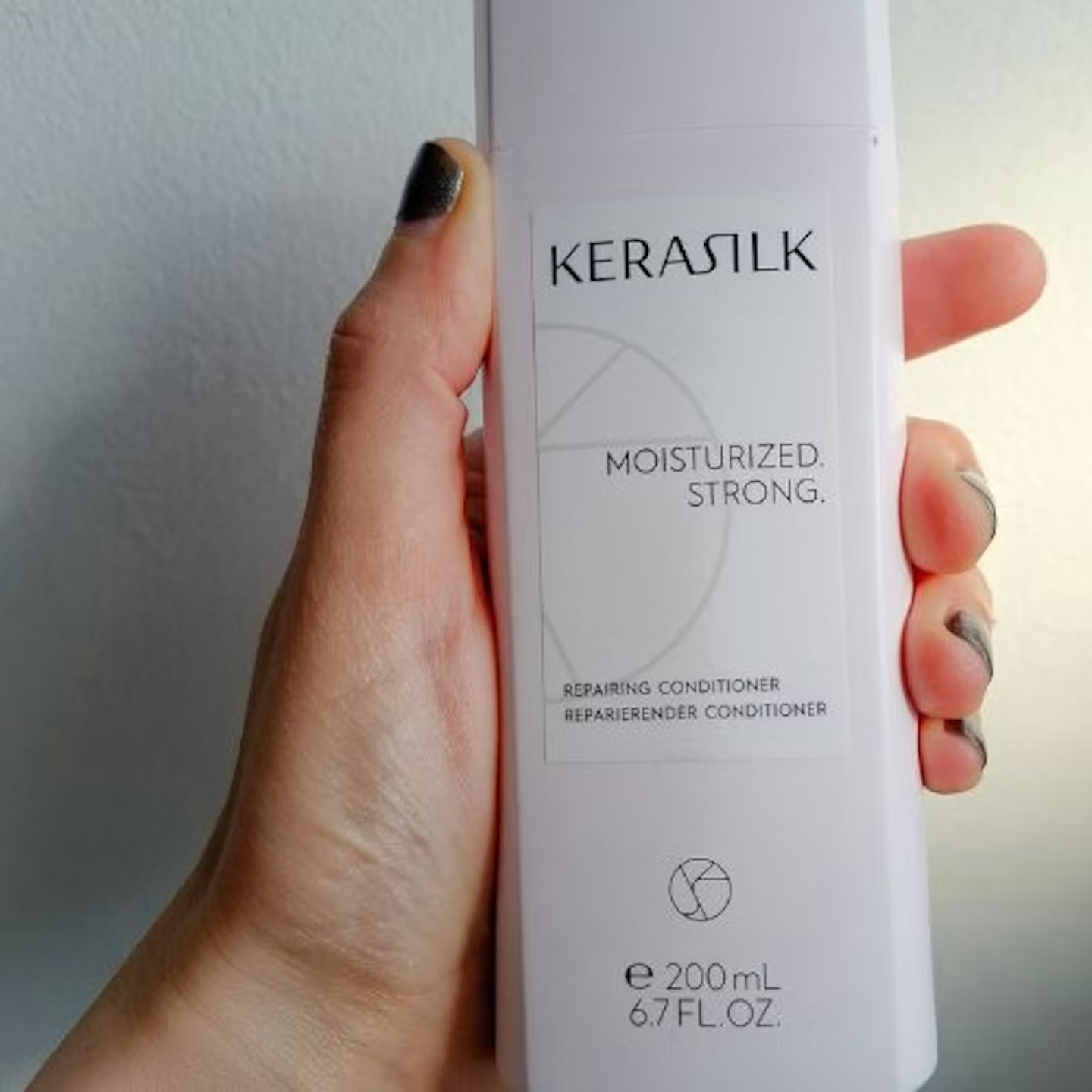 Tester holding the Kerasilk Repairing Conditioner for Dry, Damaged Hair