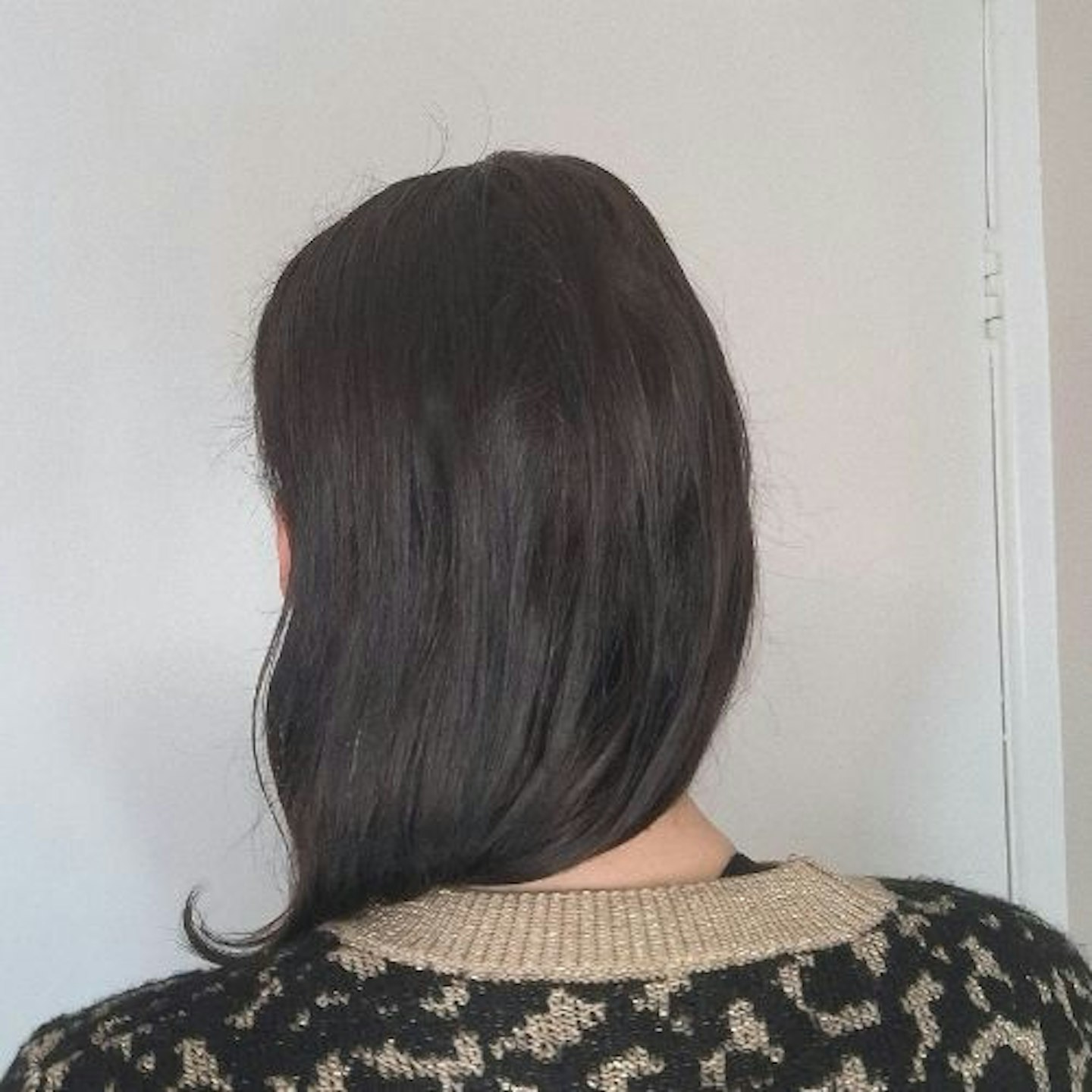 back view of testers' glossy, straightened, dark brown hair against a neutral background