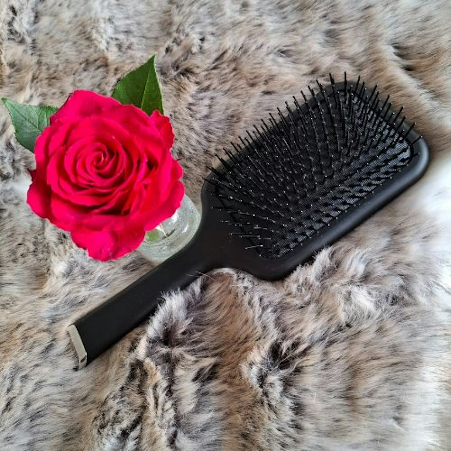 photo of ghd paddle brush next to a red rose on a fur throw