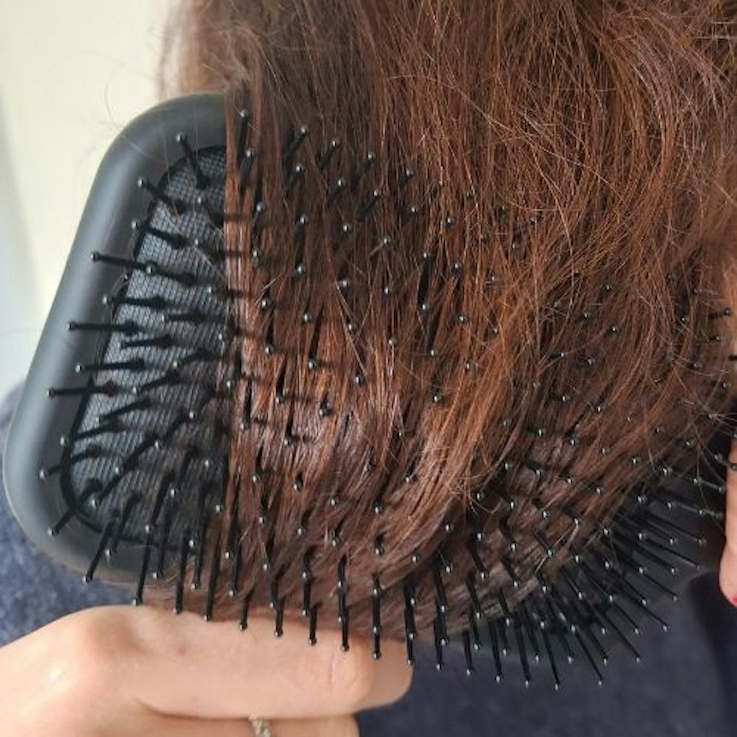 close-up of tester brushing brown hair with a ghd paddle brush