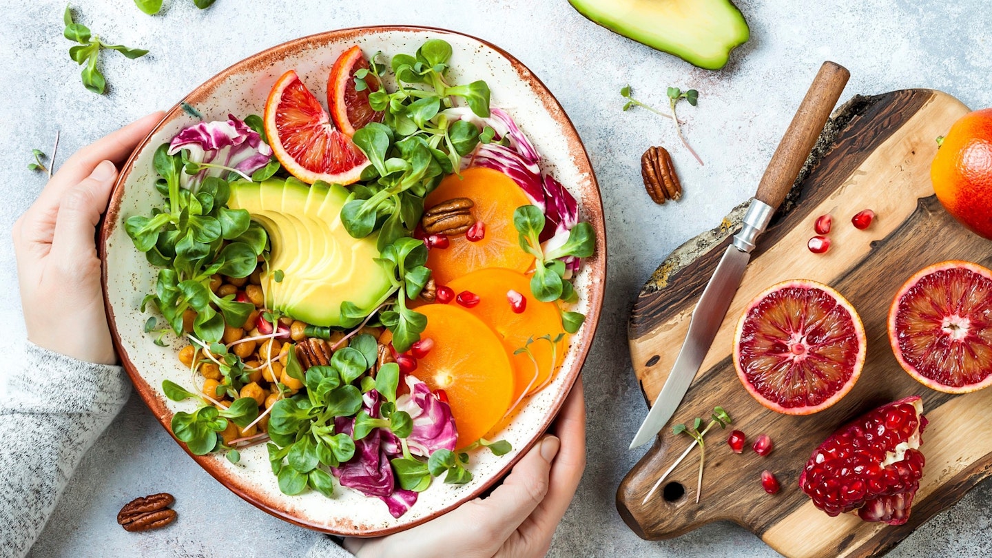 Buddha bowl with turmeric roasted chickpeas, greens, avocado, persimmon, blood orange, nuts and pomegranate