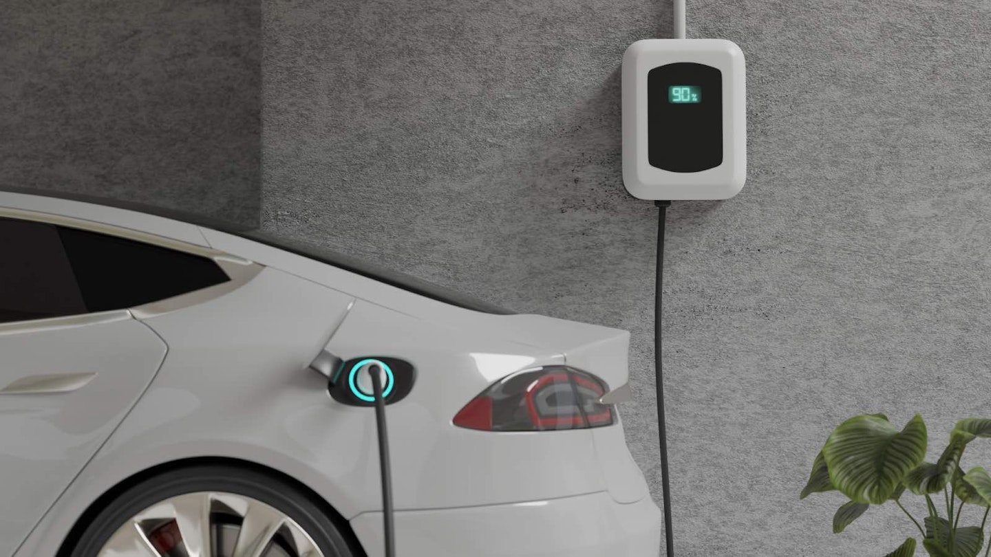 White EV car charging with a green cable against a grey background