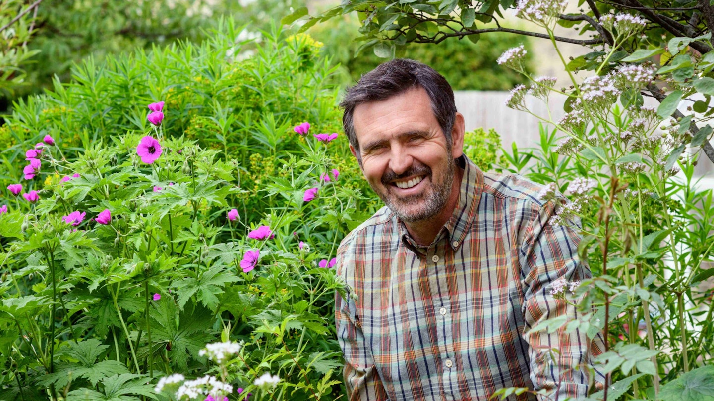 Adam Frost in garden with pink flowers