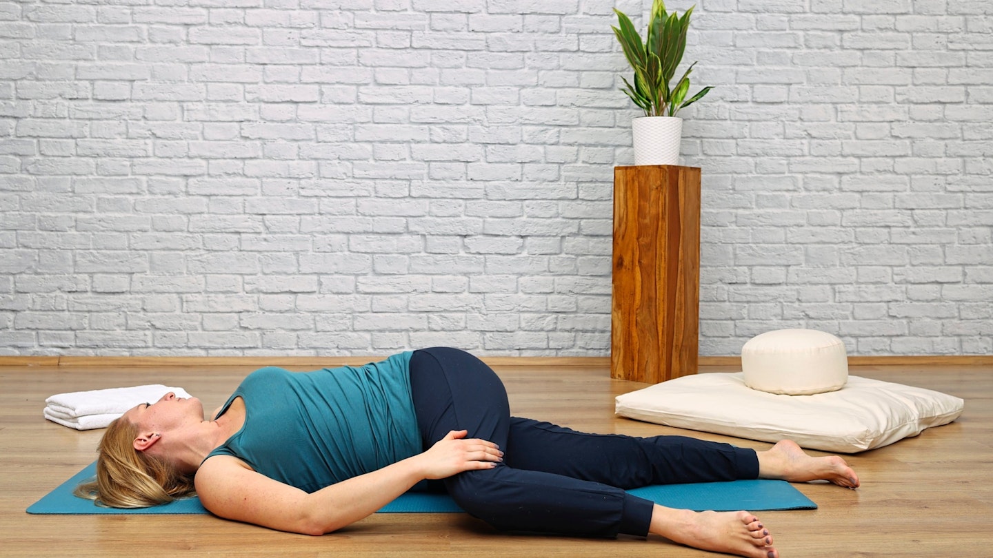 Woman doing a spinal stretch while lying on a yoga mat