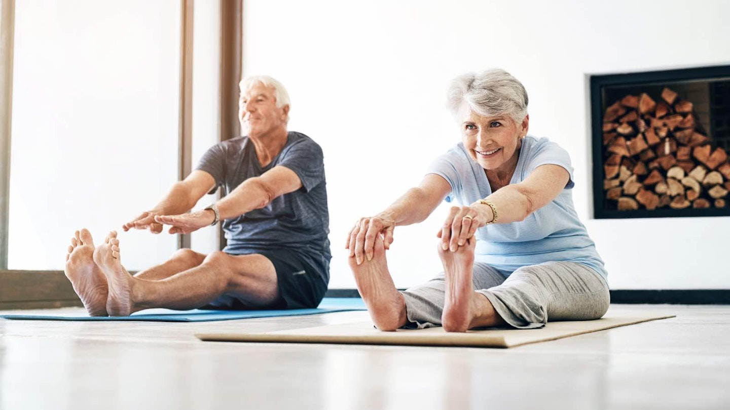 Man and woman reaching for their toes while seated