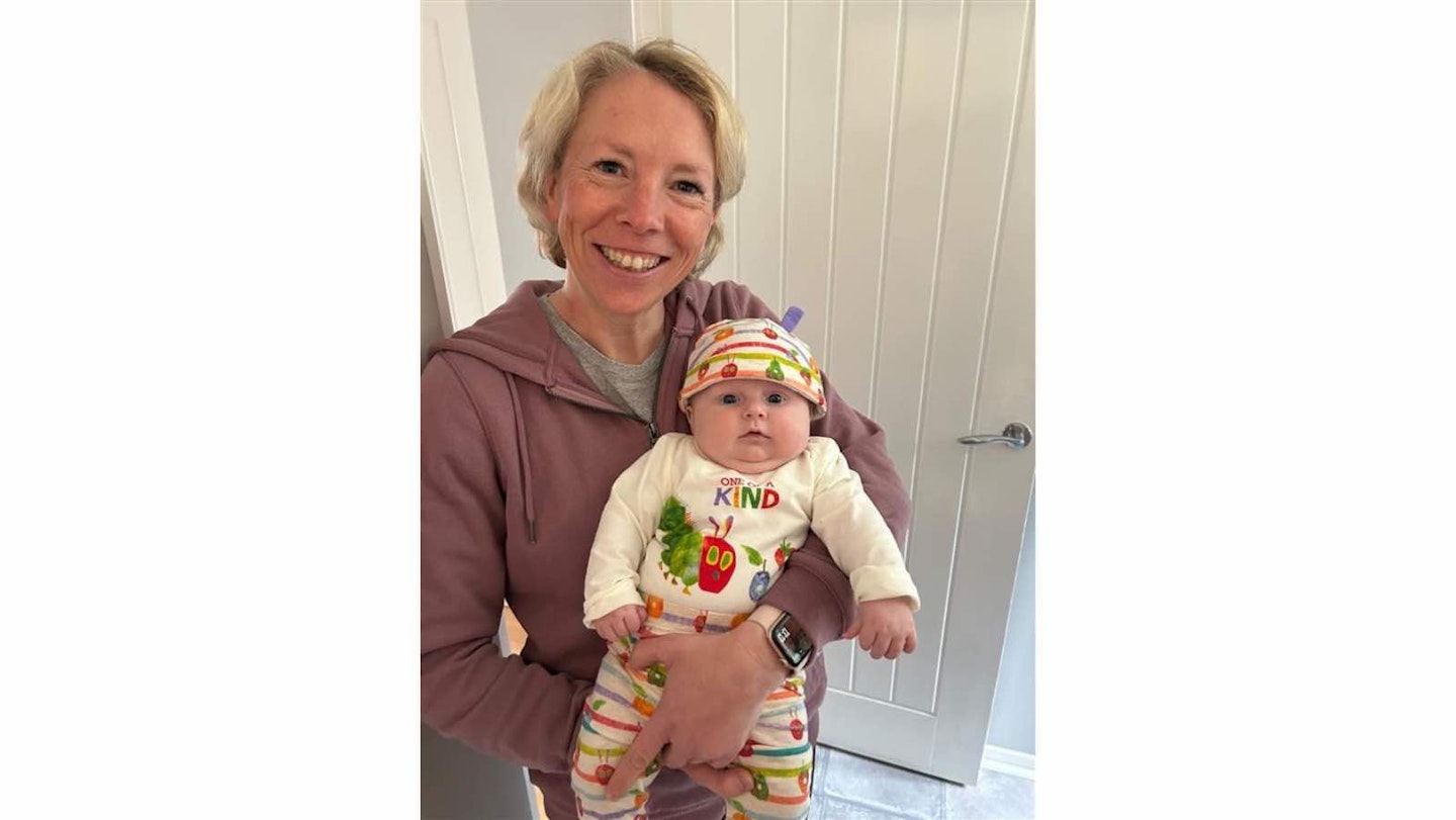 Becky Fuller with Invisalign aligners in. Holding a bonus baby,