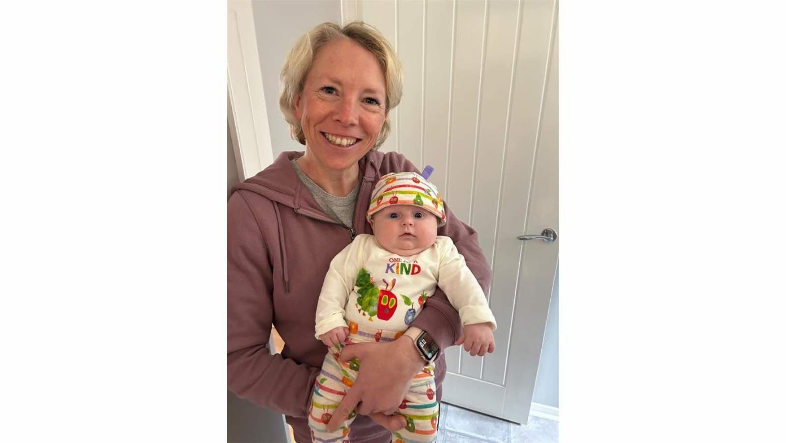 Becky Fuller with Invisalign aligners in. Holding a bonus baby,