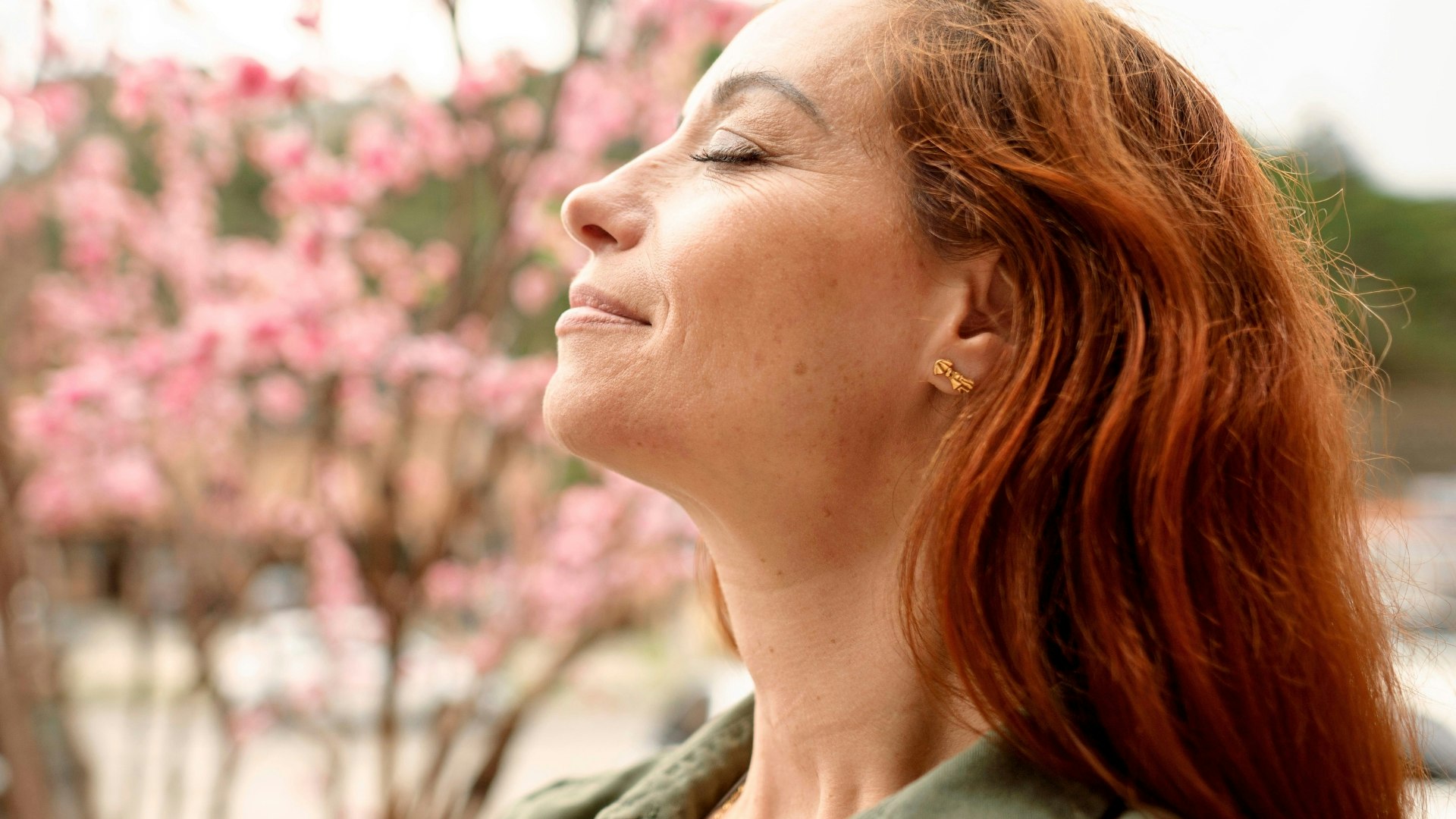 Woman with her eyes closed, breathing in the outdoors