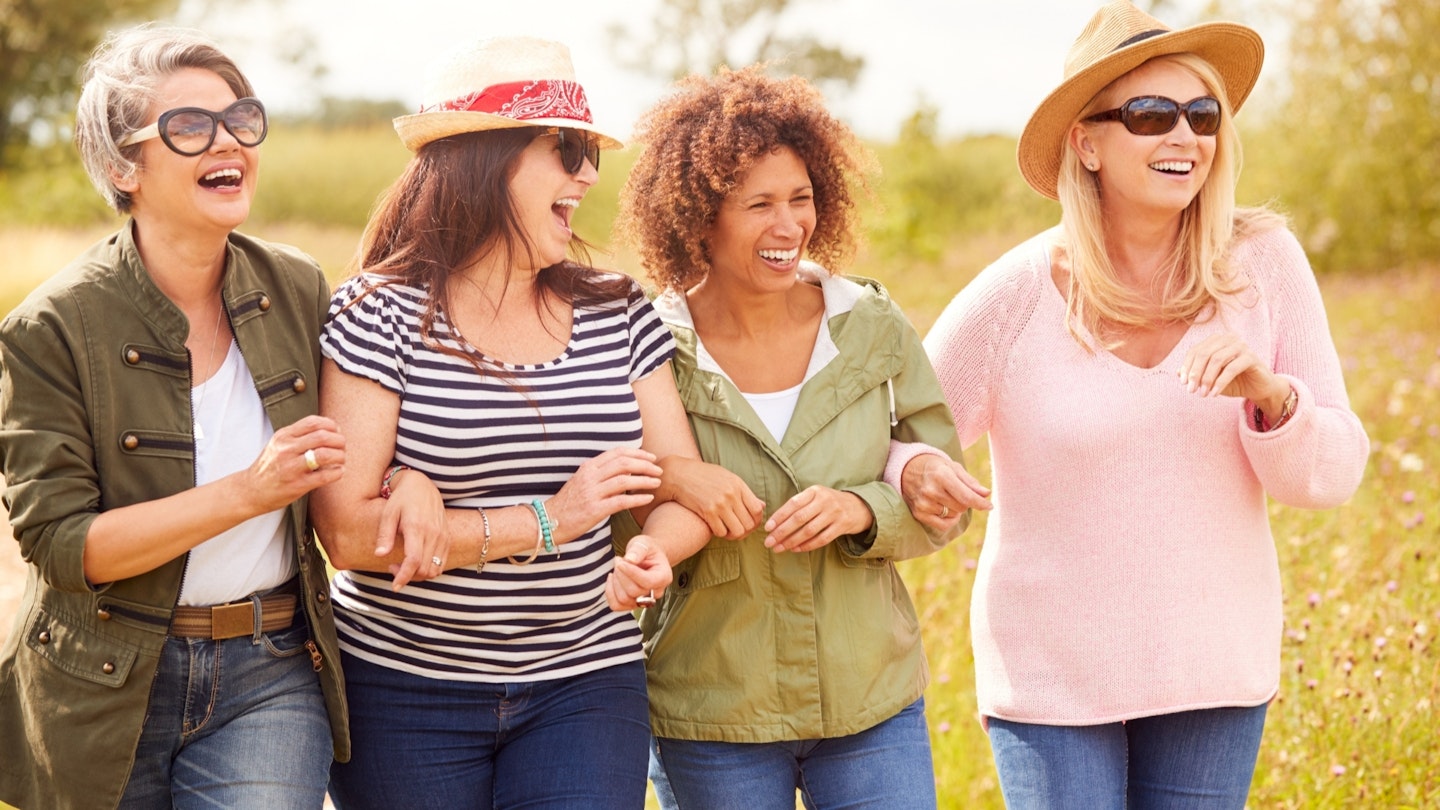 Four women linking arms walking