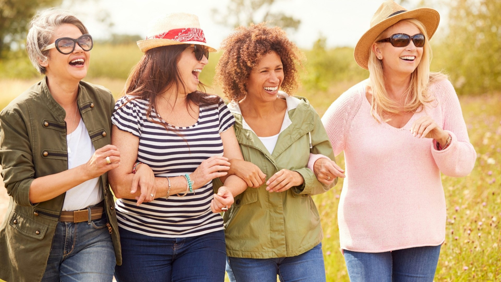 Four women linking arms walking