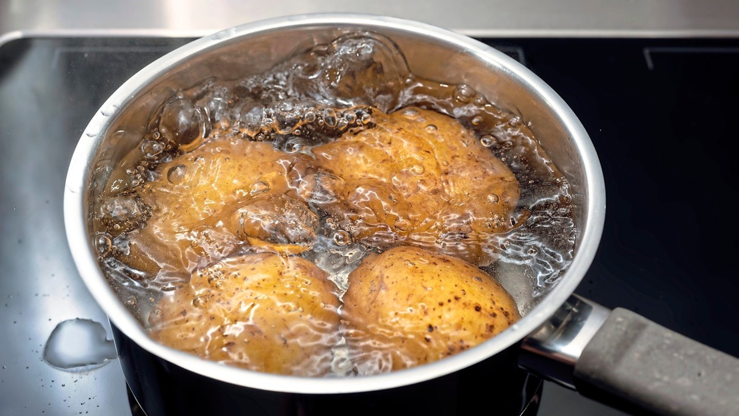 cooking potatoes in boiling water in a stainless steel pot on the stove