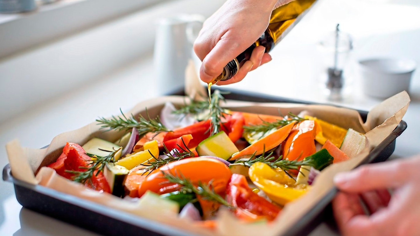 Close Up Of Seasoning Tray Of Vegetables For Roasting With Olive Oil