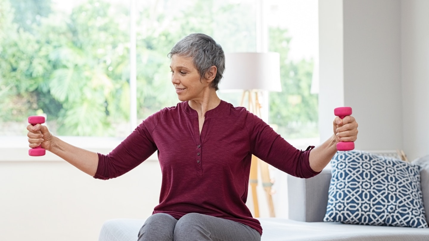 Woman sitting down doing exercise with weights