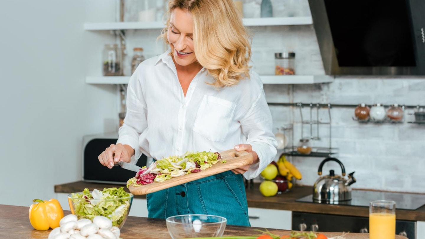 A lady putting lettuce from a chopping board into a bowl