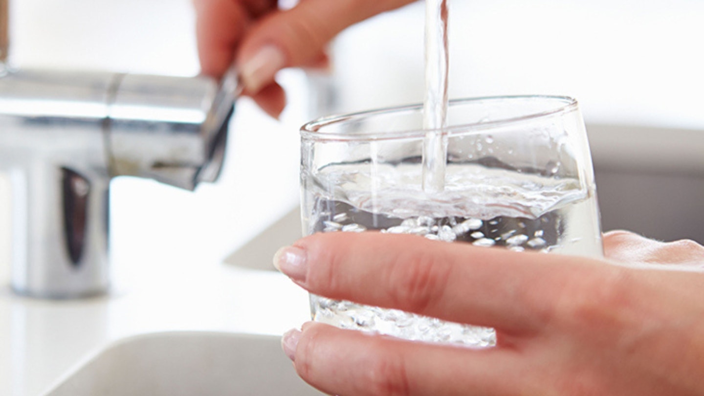 lose Up Of Woman Pouring Glass Of Water From Tap In Kitchen