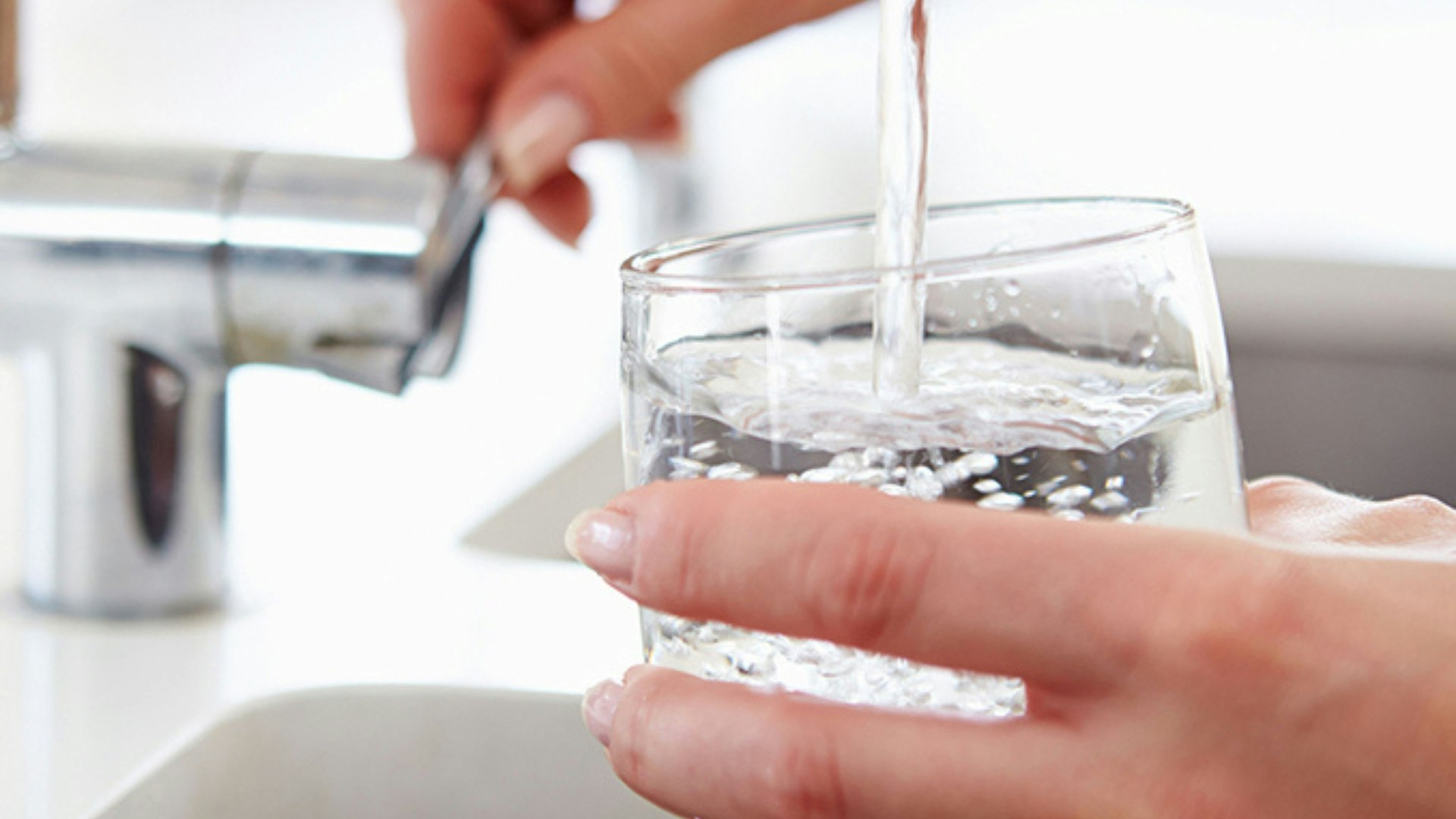 lose Up Of Woman Pouring Glass Of Water From Tap In Kitchen