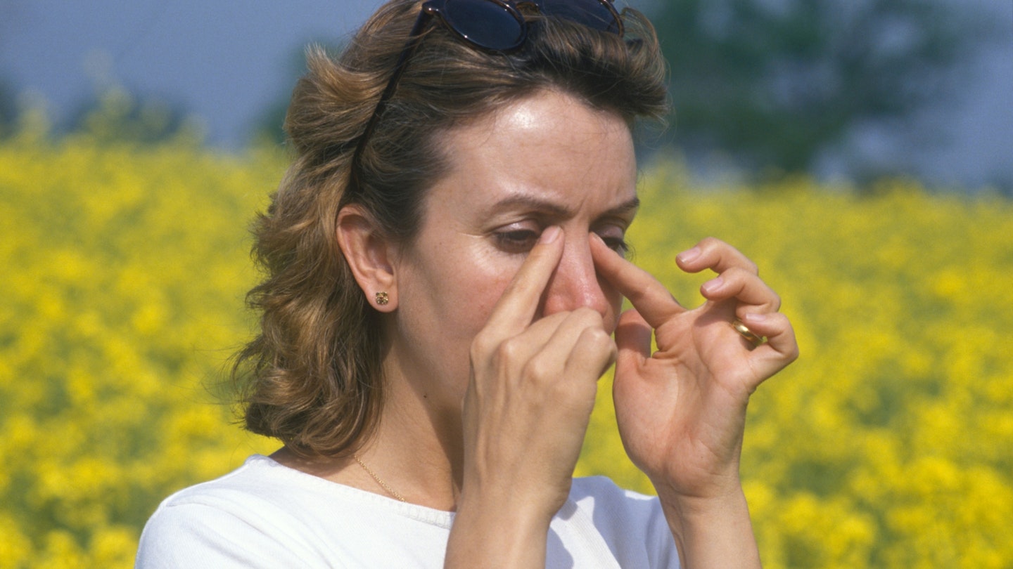 woman with hay fever in a field of rape flowers