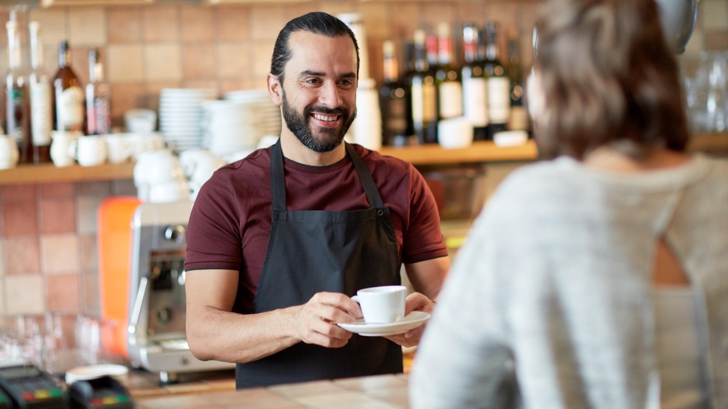 man or waiter serving customer in coffee shop