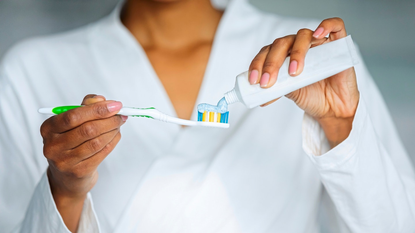Woman applying toothpaste on toothbrush
