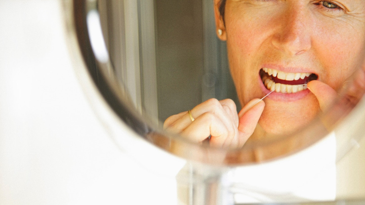 Woman flossing in the mirror