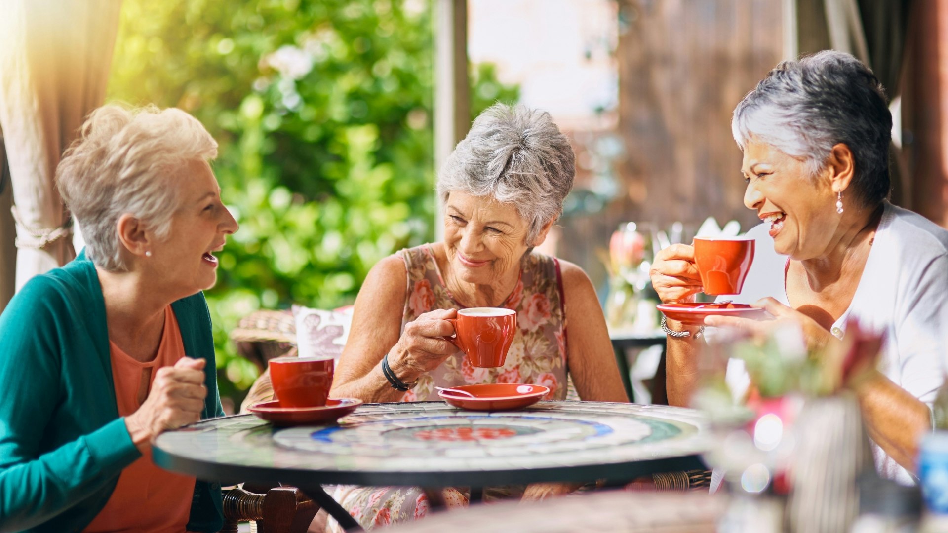 Three ladies laughing enjoying a drink together