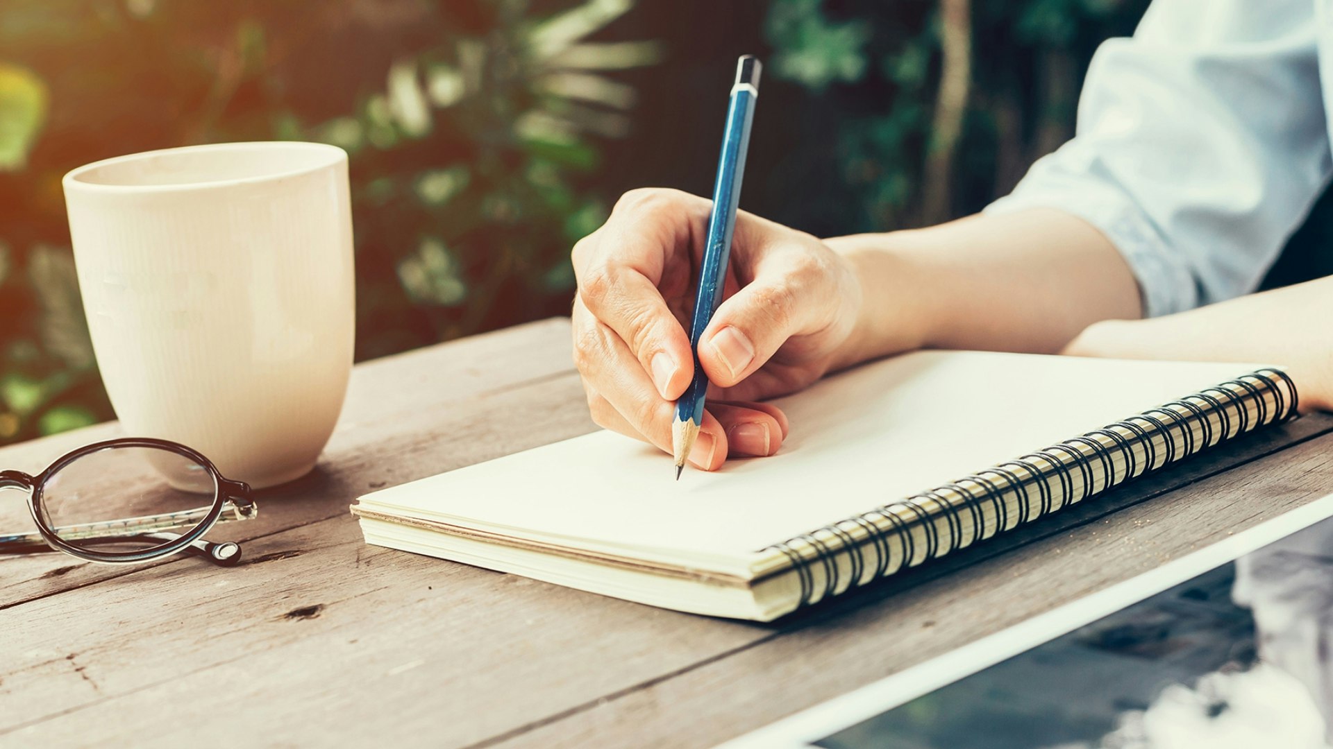 Someone writing in a notepad with a pencil