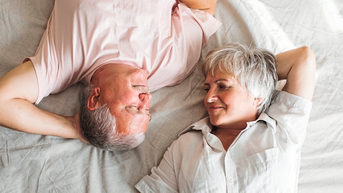Happy elderly couple wakes up in bed in the morning.
