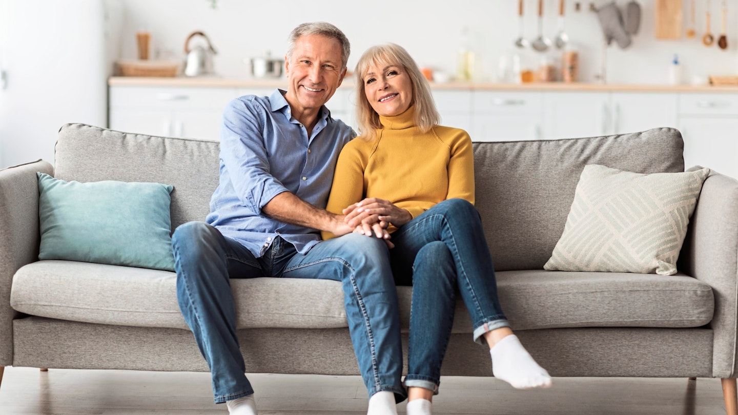 Cheerful Senior Spouses Holding Hands Hugging Sitting On Sofa