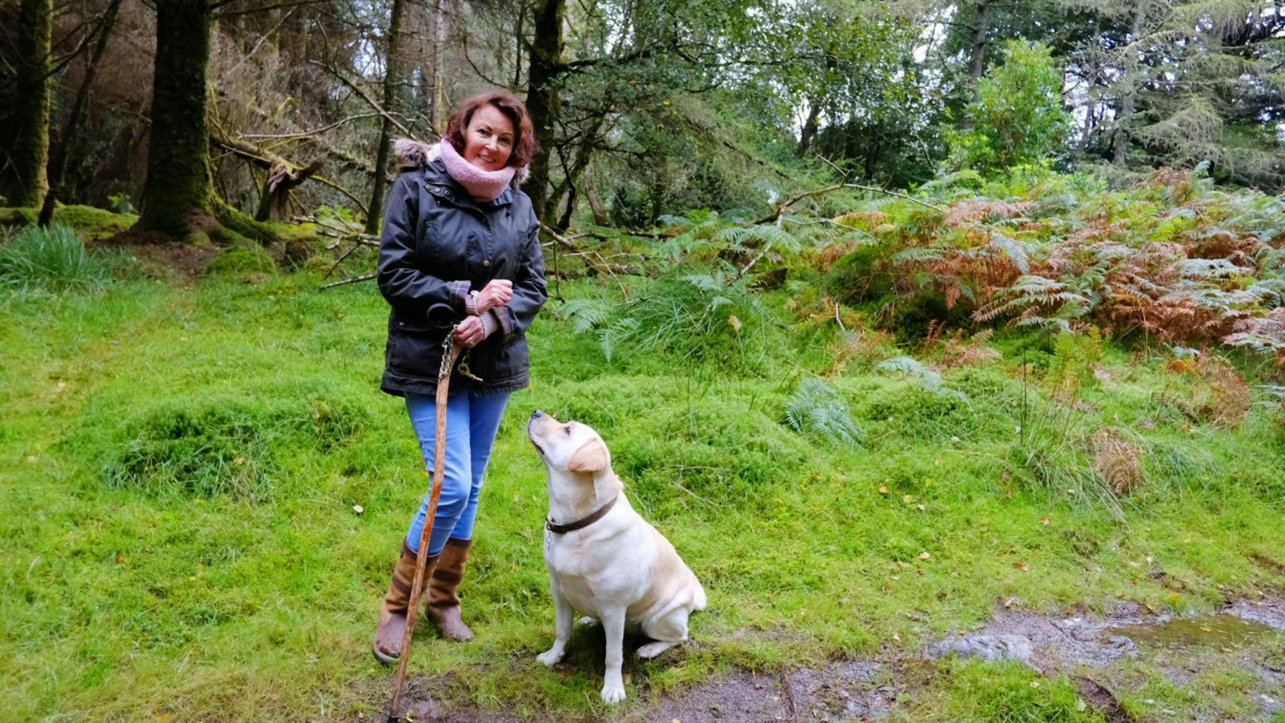 Mature woman outdoors with her yellow Labrador