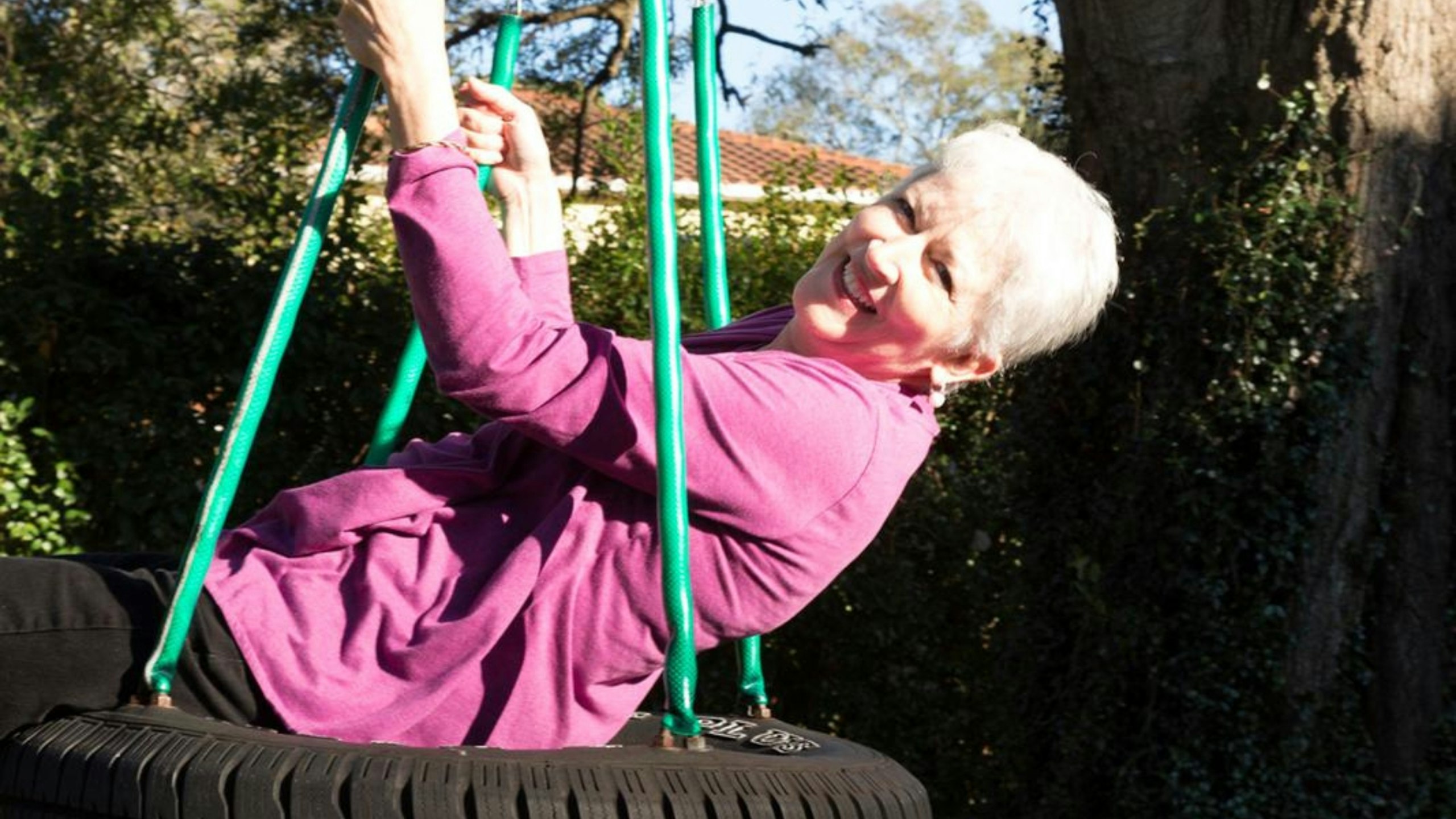 Happy Mature Woman Playing on a Tire Swing